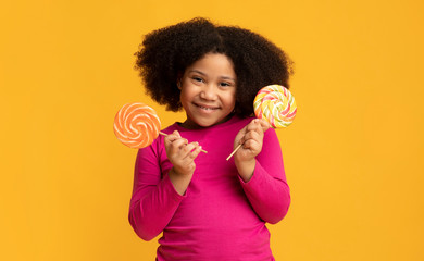 Pretty Little Black Girl Posing With Two Colorful Lollipops In Hands