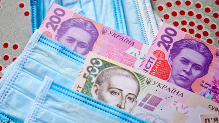 Medical masks with money. Ukrainian money with protective masks. A fan of Ukrainian hryvnia with a fan of medical masks.