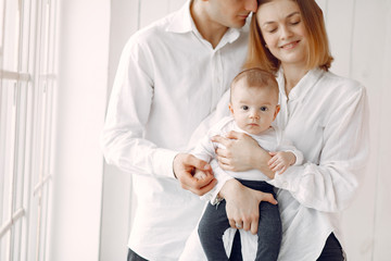 Cute family in a room. Lady in a white shirt. Woman hold child in her hands.