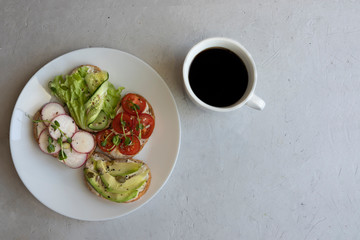 Sandwiches or tapas on a white plate with vegetable fillings and decorated with microgreens, a healthy snack sandwiches and a cup of black coffee, fast food, lunch at work, flat lay space for text