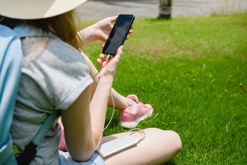 Girl charge phone with powerbank at grass