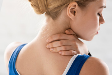 Sportswoman feeling acute pain in neck on white background