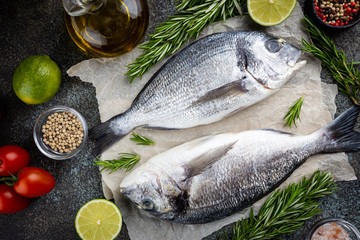 Fresh ready to cook raw bream fish dorado with ingredients and seasonings like rosemary, salt,...