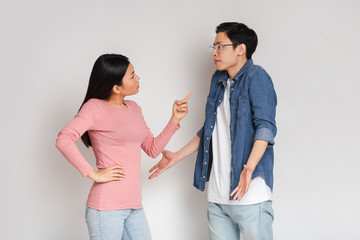 Asian angry girl scolding her surprised boyfriend