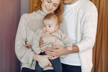 Cute family in a room. Lady in a sweater. Mothre hold her child in her hands.