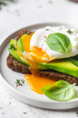 Healthy breakfast whole wheat toasted bread with avocado and poached egg over white background