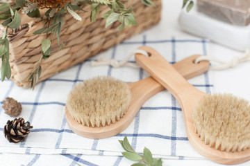 Fototapeta na wymiar wooden massage brushes with natural bristles on a towel, a basket of flowers and soap. Eco bath, healthy skin