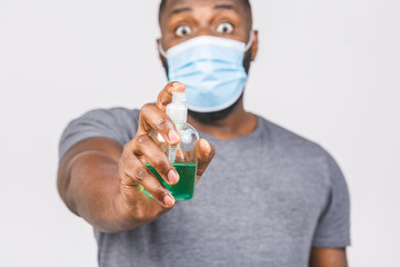 African american man in sterile face mask isolated on white background. Epidemic pandemic coronavirus 2019-ncov sars covid-19 flu virus concept. Holding bottle with antibacterial sanitizer.