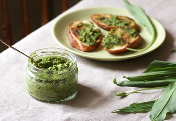 Pesto from wild garlic and fried toast from baguette on the table. Back of chair in the background. life style food