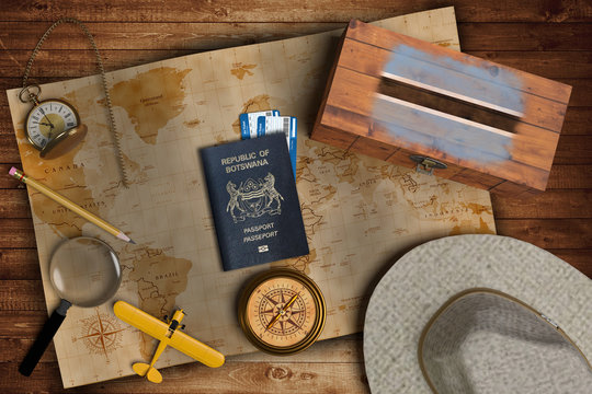 Top view of traveling gadgets, vintage map, magnify glass, hat and airplane model on the wood table background. On center, official passport of Botswana and your flag.