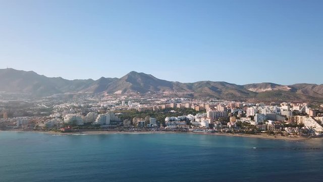 Aerial View of Benalmadena, Costa del Sol, Malaga, Spain. Panoramic view over the city and mountains in the background at the beginning of sunset, with soft warm light over the buildings