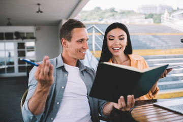 Obraz premium Smiling man and woman discussing notes in planner