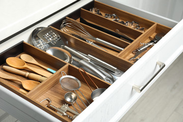 Different utensils in open desk drawer indoors, closeup