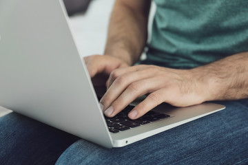 Man working on modern laptop at home, closeup