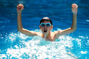 Happy swimmer boy rejoices victory in the race raising his hands up. Competition and victory concept.