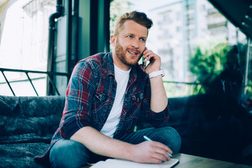 Happy businessman making appointment via phone writing in planner