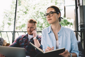 Pensive woman writing in notebook in cafe