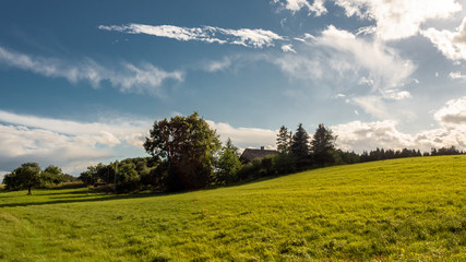 Fototapeta na wymiar Green hill under a blue sky with white clouds