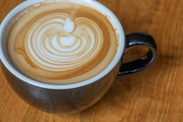 latte with foam art in mug on wooden table