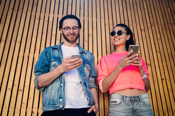 Below view of happy millennial friends sharing media content via cellphone technology using...