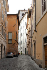 A narrow alley in the center of Rome. Medieval buildings. There's no one on the street.