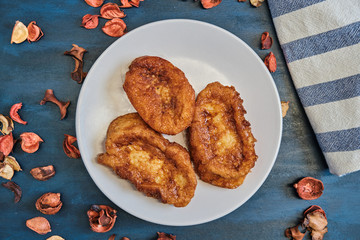 Traditional homemade Spanish torrijas on blue wooden background  with flower ornament and a cloth. Easter typical dessert.