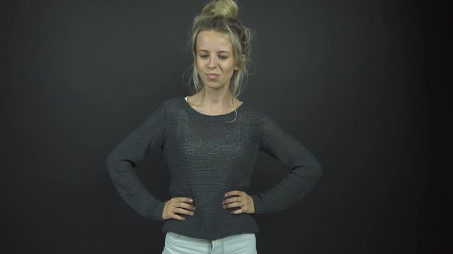 blonde in grey pullover pulls faces standing on stage