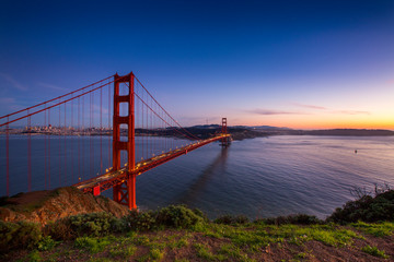 Sunset over the Golden Gate Bridge with the skyline of San Francisco, California in the background.