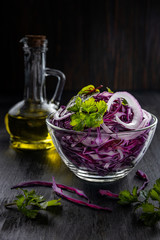 Red cabbage salad with olive oil on a black background in rustic style, shallow depth of field, selective focus, moonlight highlight. Healthy food concept.