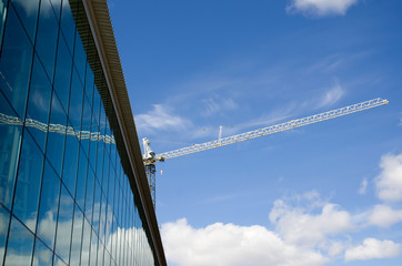 Fototapeta premium Construction Crane Over a Glass Building with Blue Sky