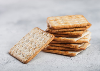 Stack of square organic crispy and salty crackers on light table.