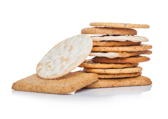 Stack of various organic crispy wheat, rye and corn flatbread crackers with sesame and salt on white.