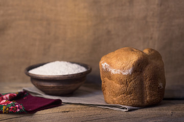 Village freshly baked bread on a table with eggs and flour
