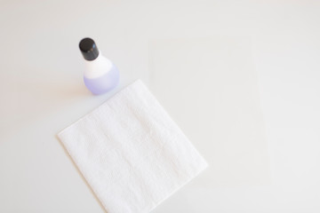 Acetate, kitchen paper and cleaning liquid on a white surface.