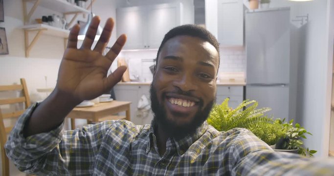 Cheerful african am waving hand during video conference staying home