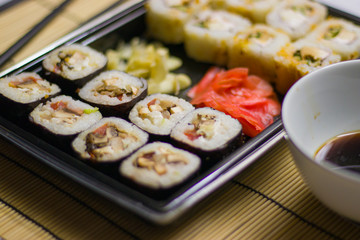 japanese cuisine different rolls with black chopsticks red pickled ginger wasabi sauce and soy sauce on the table
