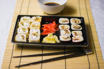 japanese cuisine different rolls with black chopsticks red pickled ginger wasabi sauce and soy sauce on the table