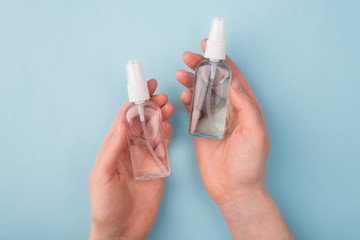 Prevent illness concept. Top above overhead closeup view photo of hands holding two bottles with antibacterial liquid inside isolated over pastel blue color background