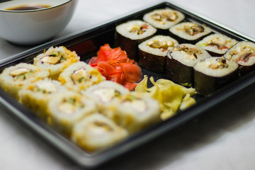 japanese cuisine different rolls with black chopsticks red pickled ginger wasabi sauce and soy sauce on the table