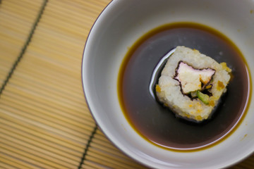 japanese food roll with black chopsticks and soy sauce in a white plate on the table