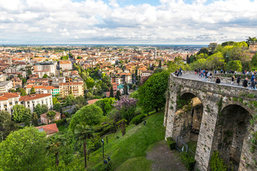 Fototapeta na wymiar Aerial panorama of Bergamo city, Lombardy, Italy. Picturesque spring view from one of the viewpoints of upper city of Bergamo. Pedestrian street Via SantAlessandro and Porta San Giacomo on the right