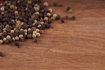 Close up of condiment on brown wooden background. Bunch of different peppers on table with space for your text.