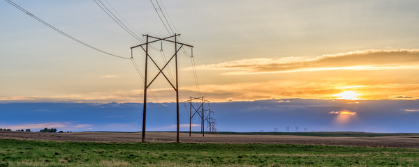 Power lines and poles at southwest Saskatchewan prairies during sunset