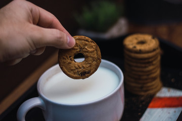 Fototapeta premium mano metiendo una galleta en un tazón de leche