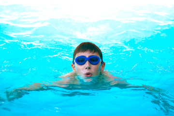 Naklejka premium Teen boy swims in the pool. Healthy lifestyle concept. Close-up.
