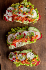open sandwich with beetroot hummus with vegetables and tomato sauce. Healthy vegan food concept.