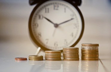 Vintage alarm clock and group of growing coins placed on the floor, selective focus and shallow depth of field, investment concept. growing on coin, Business Finance and Save Money.