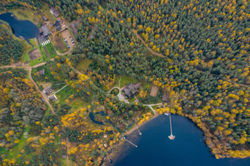 Drone view point of rural area in Autumn with lake Boroye, The big wooden house in forest, Piers on the lake, Valday national park, Russia, panoramic image, golden trees, Wooden lodges, cloudy weather