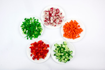plates on a white background with finely chopped slices of vegetables, salad ingredients, vegetable mix, healthy food and organic vegetarian products, isolate, place for text