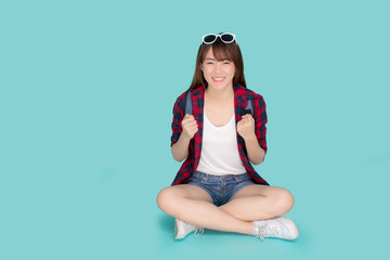 Beautiful portrait young asian woman wear sunglasses on head smile excited summer holiday isolated blue background, asia girl sitting cheerful while vacation trip, travel concept.